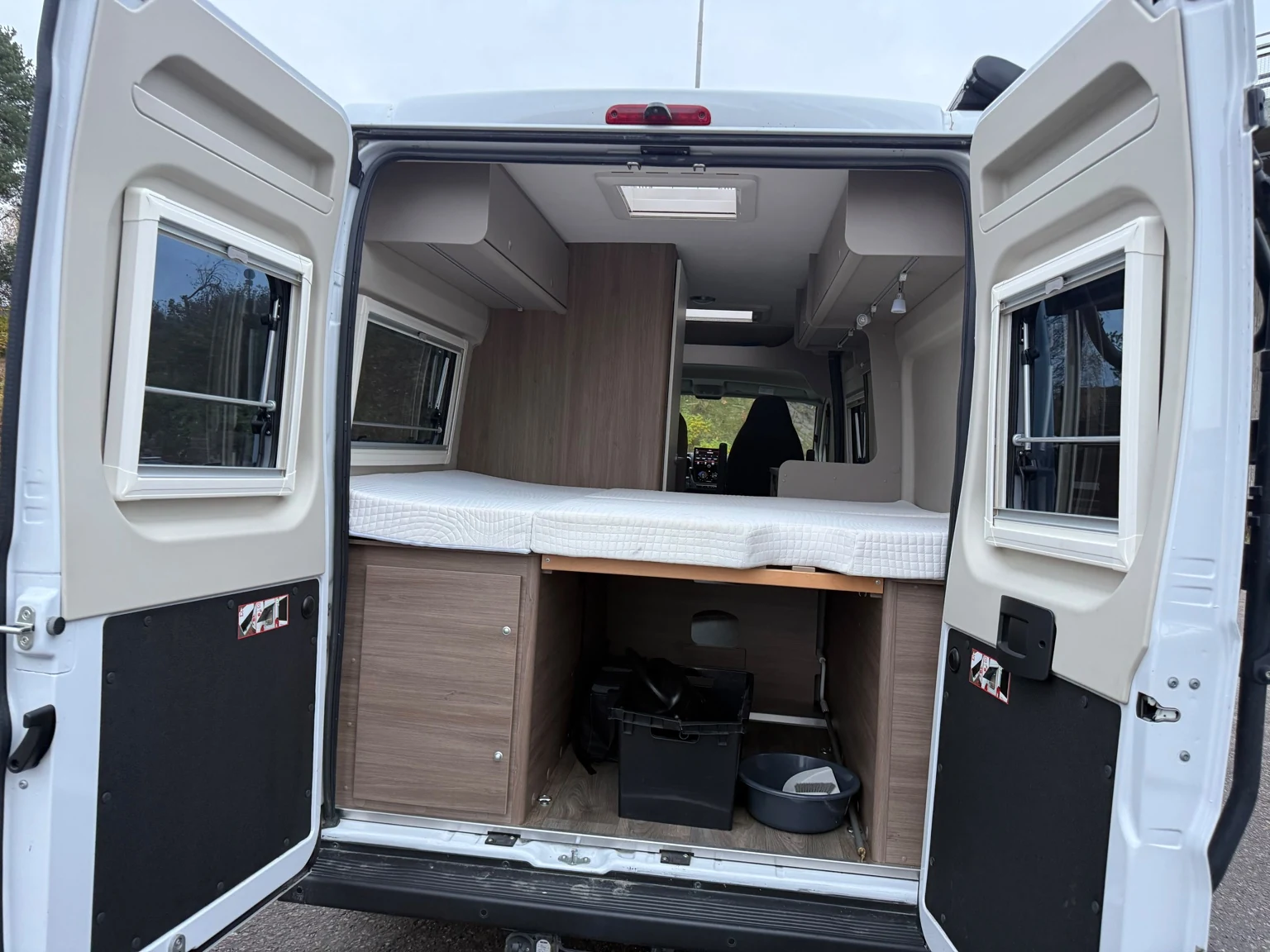 Takaovista näkyvä vuoteen alainen tavaratila, vasemmanpuoleinen kaappi ja säilytyslaatikot